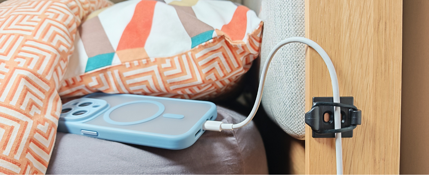Phone charging cable secured by bed.