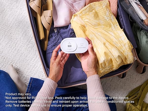 Kidde AA battery CO detector being packed in a suitcase for travel safety, mobile image