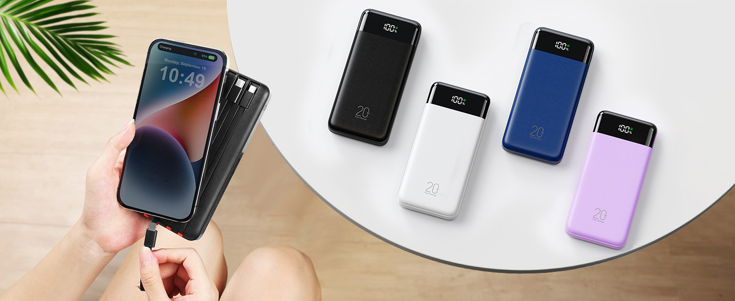 Five portable power banks in different colors—black, white, blue, and purple—displayed with charging cables on white circular surface with tropical plant leaf.