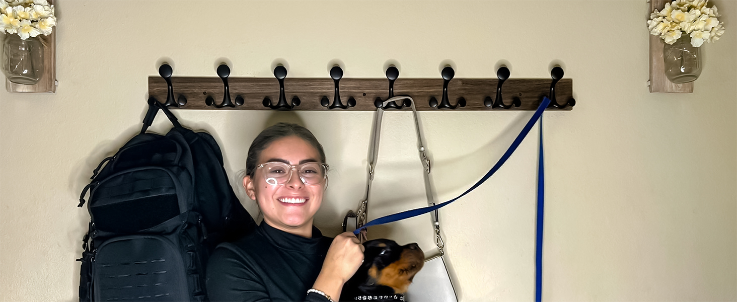 In front of the wall coat rack, a girl is happily hugging her dog.