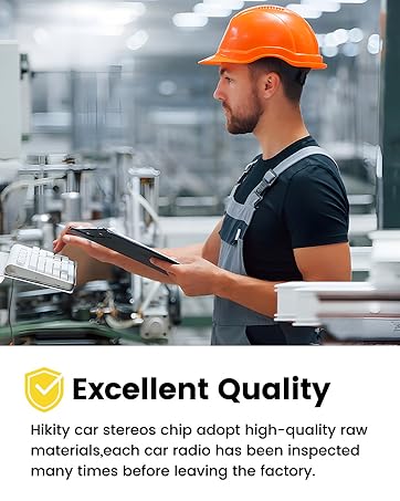 Industrial worker in black shirt and orange hard hat examining documentation in a manufacturing facility.