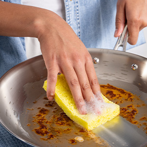 Person using Dawn Platinum to clean a greasy pan.