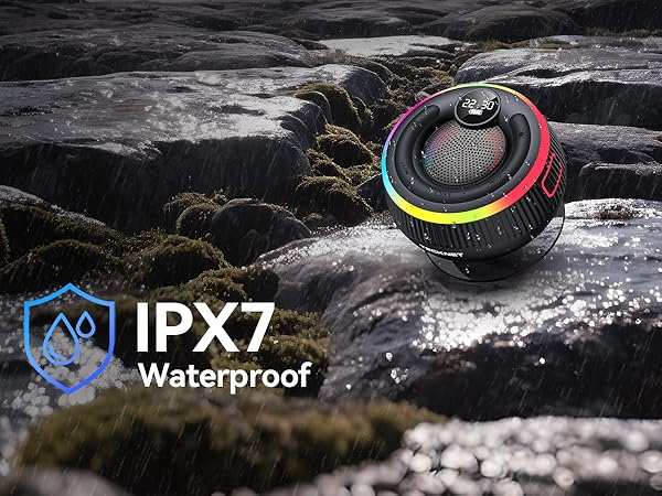 Text reads 'IPX7 Waterproof'. Black circular device shown on wet rocks, demonstrating water resistance capability.