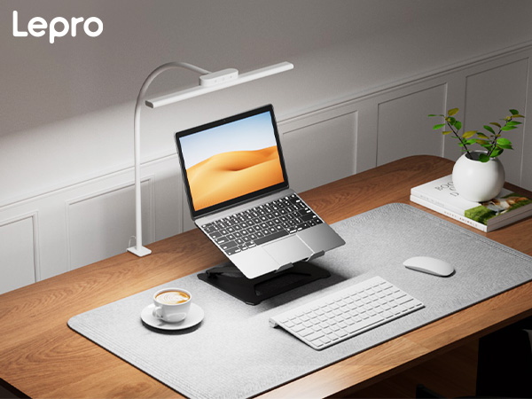 Text reads 'Lepro'. Modern desk setup with laptop stand, wireless keyboard, mouse, desk lamp, and small plant against gray wall.