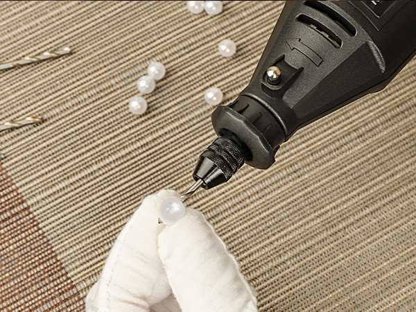 Close-up of a black rotary tool removing lint from a light-colored fabric surface on a textured background.