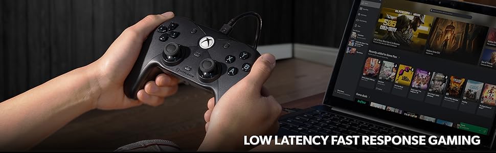 Person gaming with black controller connected to laptop.