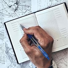 Photo shows person writing in travel planner with G2 pen