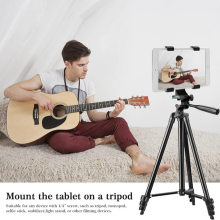 Man playing guitar while a tablet is securely mounted on a tripod holder in front of him