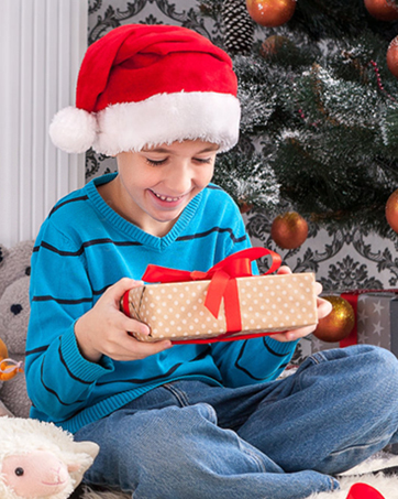 A festive holiday scene showing a wrapped gift with polka dot pattern and red bow against a Christmas tree background.