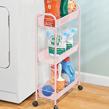 pink rolling trolley cart with detergent, dryer balls, lint roller next to white washing machine