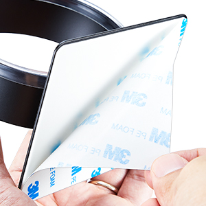 Close-up of hands peeling off an adhesive backing from a black surface-mounted object.
