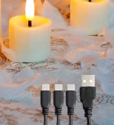 Four black USB connectors on a cable, positioned in front of a lit white candle on a sandy surface with scattered small white stars.