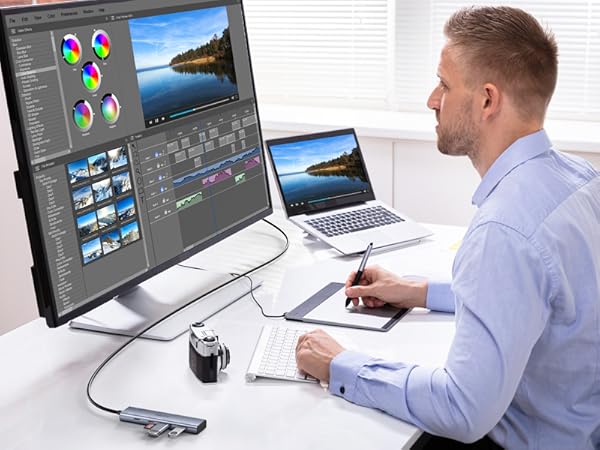 Professional workspace setup with large monitor displaying video editing software, connected to laptop and graphics tablet for content creation.