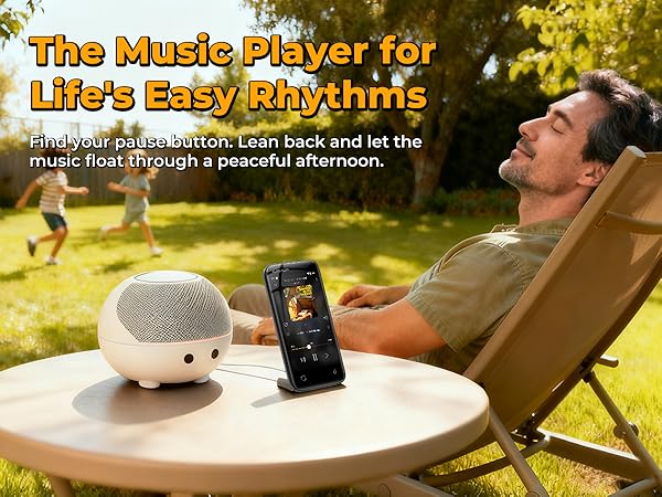 MP3 player on a table with a speaker, while a person relaxes in the yard on a sunny day
