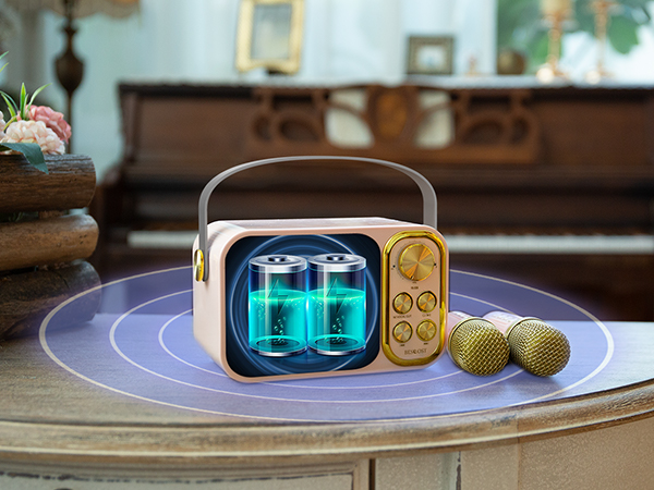 Retro-style portable speaker with glowing blue display, gold accents, and handle, placed on purple tray with two microphones nearby.