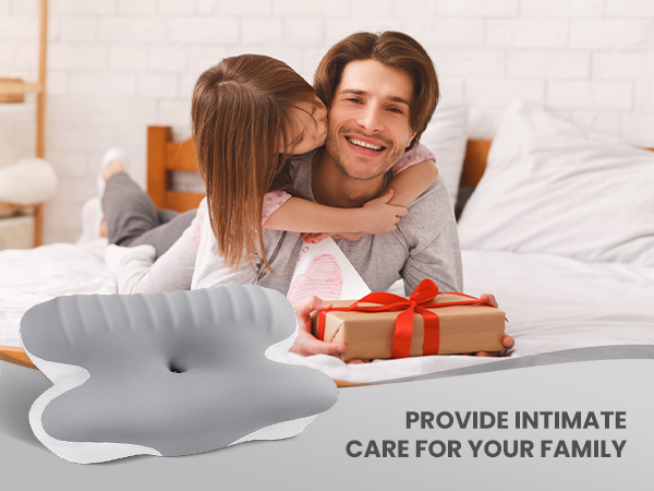 Gray dolphin-shaped object in foreground. Gift box with red ribbon on bed. Text reads 'PROVIDE INTIMATE CARE FOR YOUR FAMILY'.