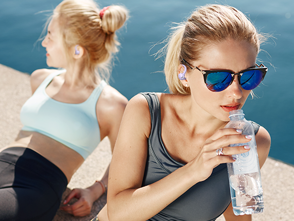 Athletic wear advertisement showing water bottle and activewear in outdoor setting with bright sunlight and blue tones.