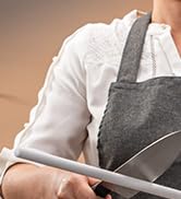 Close-up of hands holding a gray apron with pockets, suggesting kitchen or cooking context.