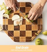 a person cutting a piece of fruit on a cutting board.