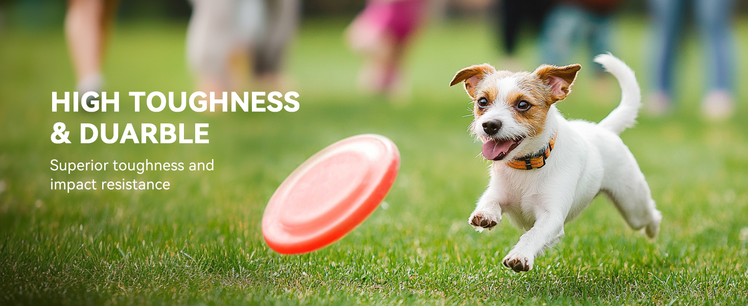 Red flying disc toy for dogs, advertised as highly durable with superior toughness and impact resistance. Small dog chasing the disc on grass.