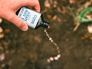Bottle of Code Blue Scrape Mate XL being poured onto a deer scrape