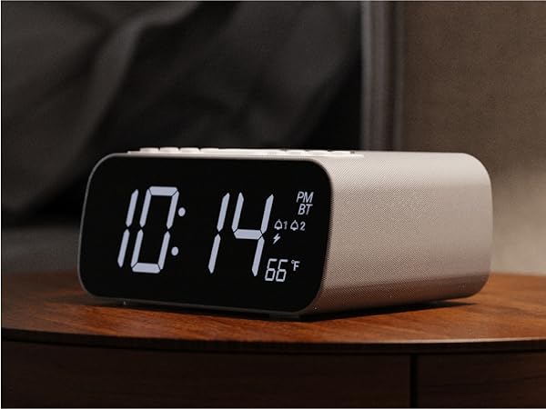 Bedside digital alarm clock shows 1014 PM and 66°F on a wooden table, soft ambient lighting, sleek