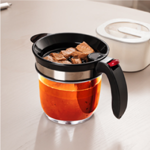 Fat separator resting on counter with food on top of colander and liquid in base.