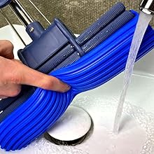 a person is cleaning a sink with a blue hose.