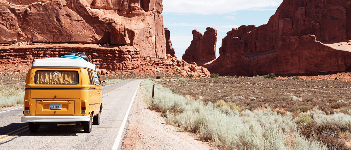 a road in the desert with a yellow van on the side