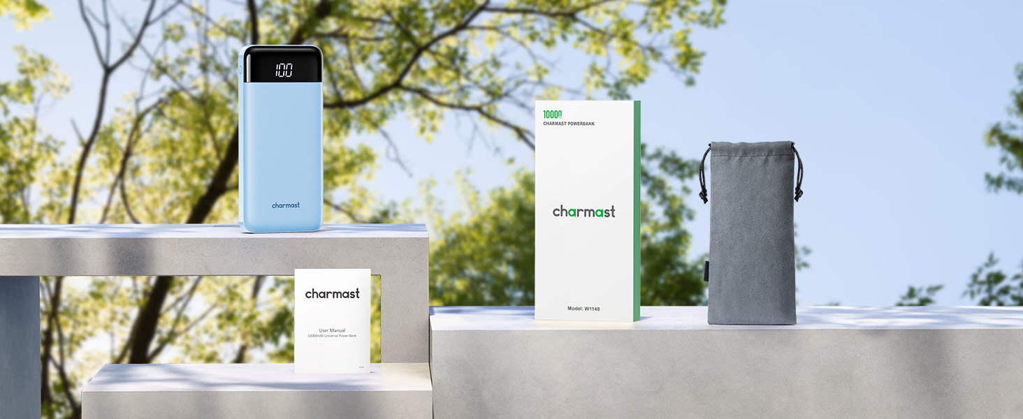 Three products on a concrete surface: a light blue rectangular device, a white box labeled 'charmost', and a gray drawstring pouch. Trees visible in background.