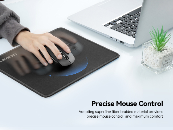 Black mousepad with wireless mouse being used on white desk surface. Small decorative plant visible. Text indicates precise mouse control with superfine fiber material.