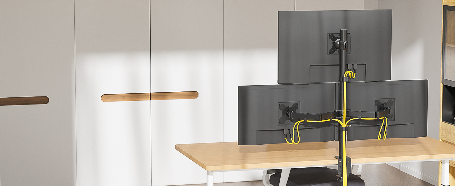 Dual monitor arm mounted on wooden desk, supporting three dark-colored computer screens. Yellow cable management visible along arm.