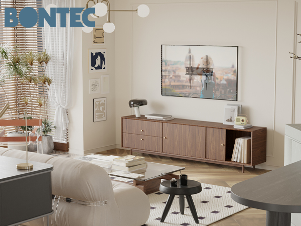 Modern living room with wooden sideboard, white armchair, round coffee table, and decorative elements. Features textured walls, pendant lights, and abstract wall art.