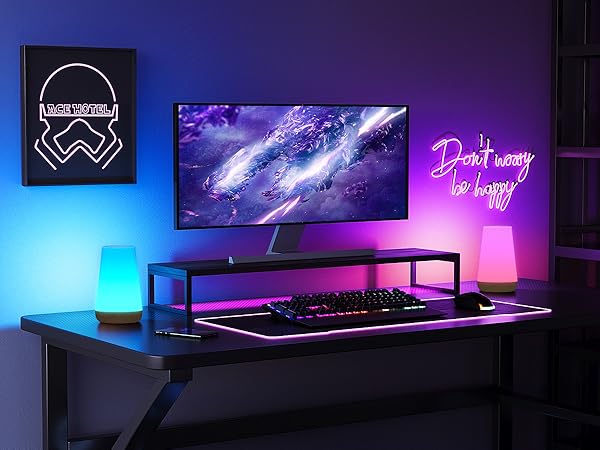 Gaming setup with curved monitor, illuminated keyboard, and neon signs. Purple and blue lighting creates ambient glow.