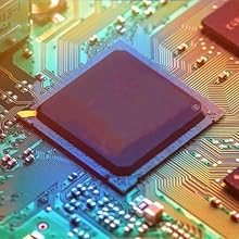 Close-up of a red computer processor chip mounted on a green circuit board. Intricate gold connection patterns visible on the board surrounding the chip.