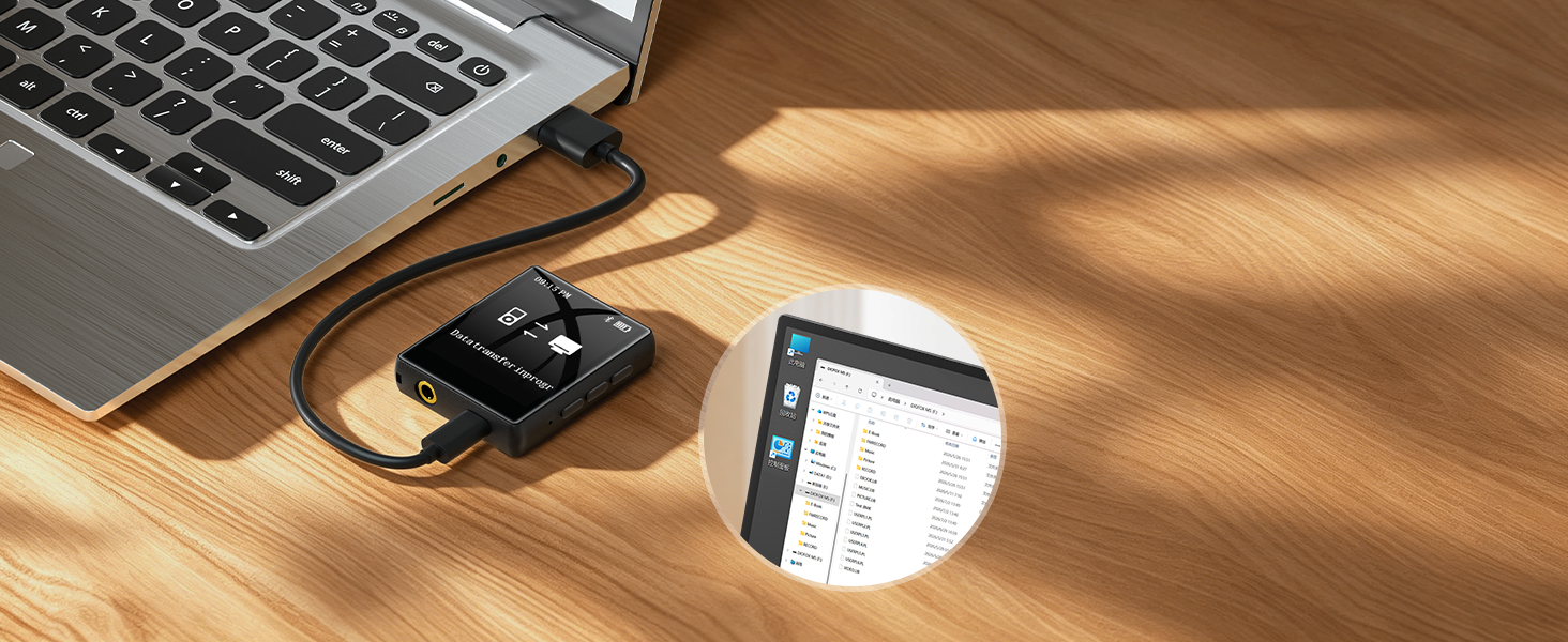 Flat lay desktop scene showing laptop corner, charger cable, and digital display device on wooden surface with natural lighting.