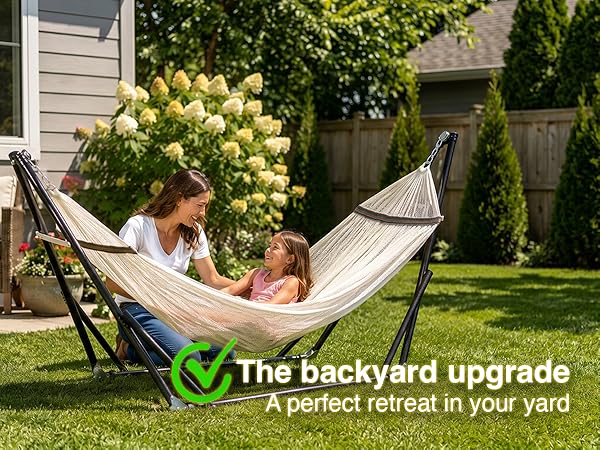 Mother and daughter relax in the comfort of their backyard on a portable hammock with stand