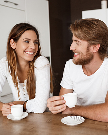 Two people enjoying coffee or tea together at a table with white cups and saucers.