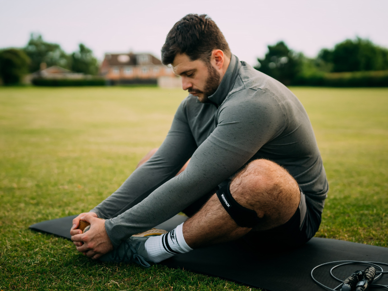 Man sitting on an exercise mat stretching