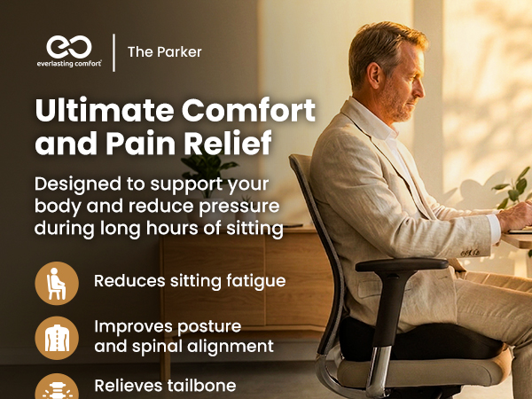 Man in business suit sits on an ergonomic office chair, working at his desk with a laptop.