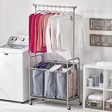 washing machine, laundry sorter, attached bar holding clothes, white shelf in a laundry room setting