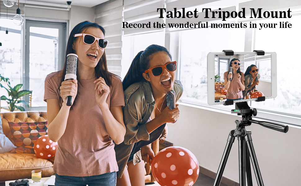 Two women singing to the camera in a living room with a tablet mounted on a tripod holder