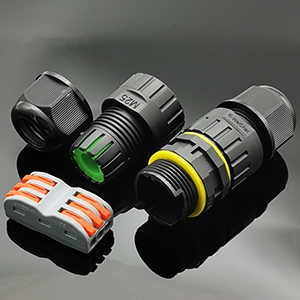 Multiple black plastic connectors or adapters with colored ring accents in yellow and green, displayed against a dark background.