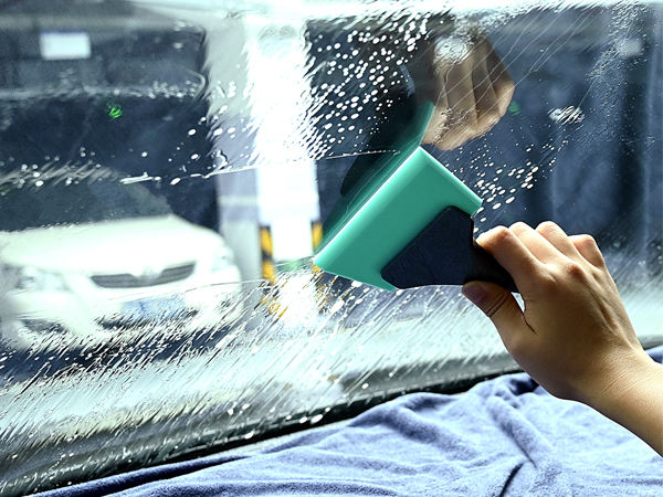 a person cleaning a car window with a brush