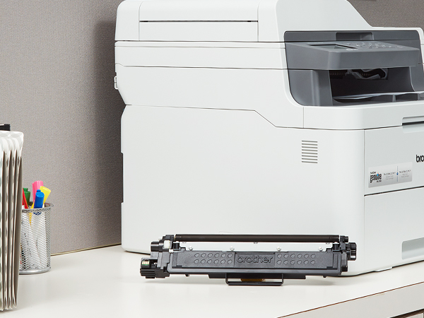 TN223BK Toner Cartridge Next to Printer