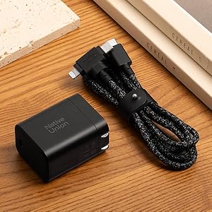 Black USB wall charger with 'Native Union' branding alongside a black braided USB cable with angled connector on wooden surface.