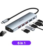 Silver USB hub with multiple ports and accessories. Text '6 in 1' visible, indicating a multi-functional device.