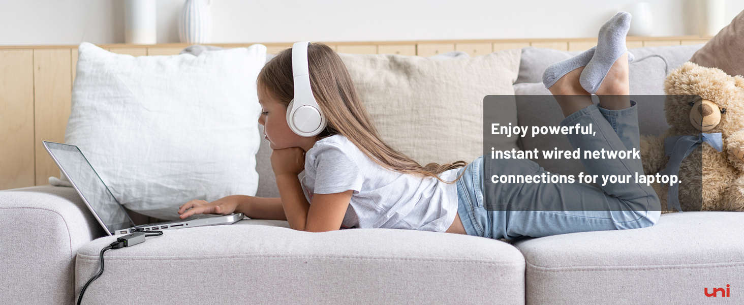 a girl laying on a couch with headphones on her head and a laptop on her lap.