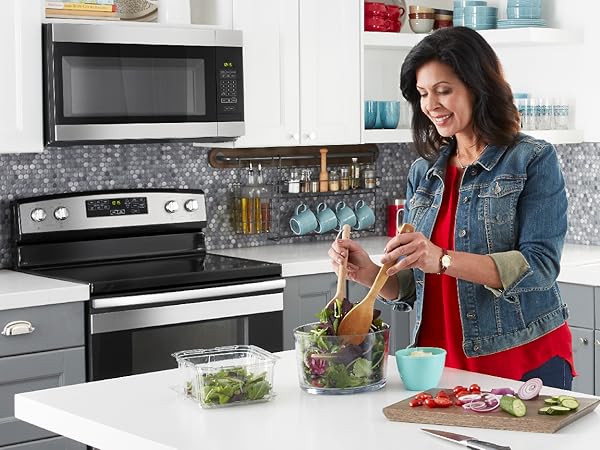 A woman making a salad in her kitchen is shown.