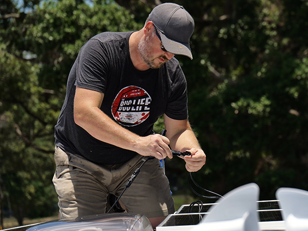 a man in a black shirt and a black hat working on a boat.